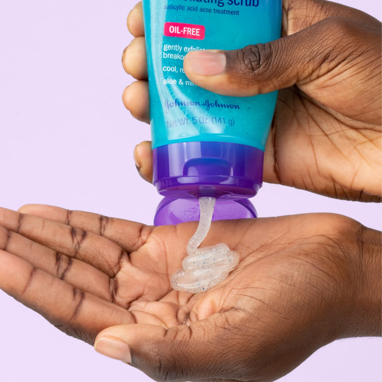 White acne Triple Clear Exfoliating Scrub squeezed in blue bottle with purple cap into palm of hand