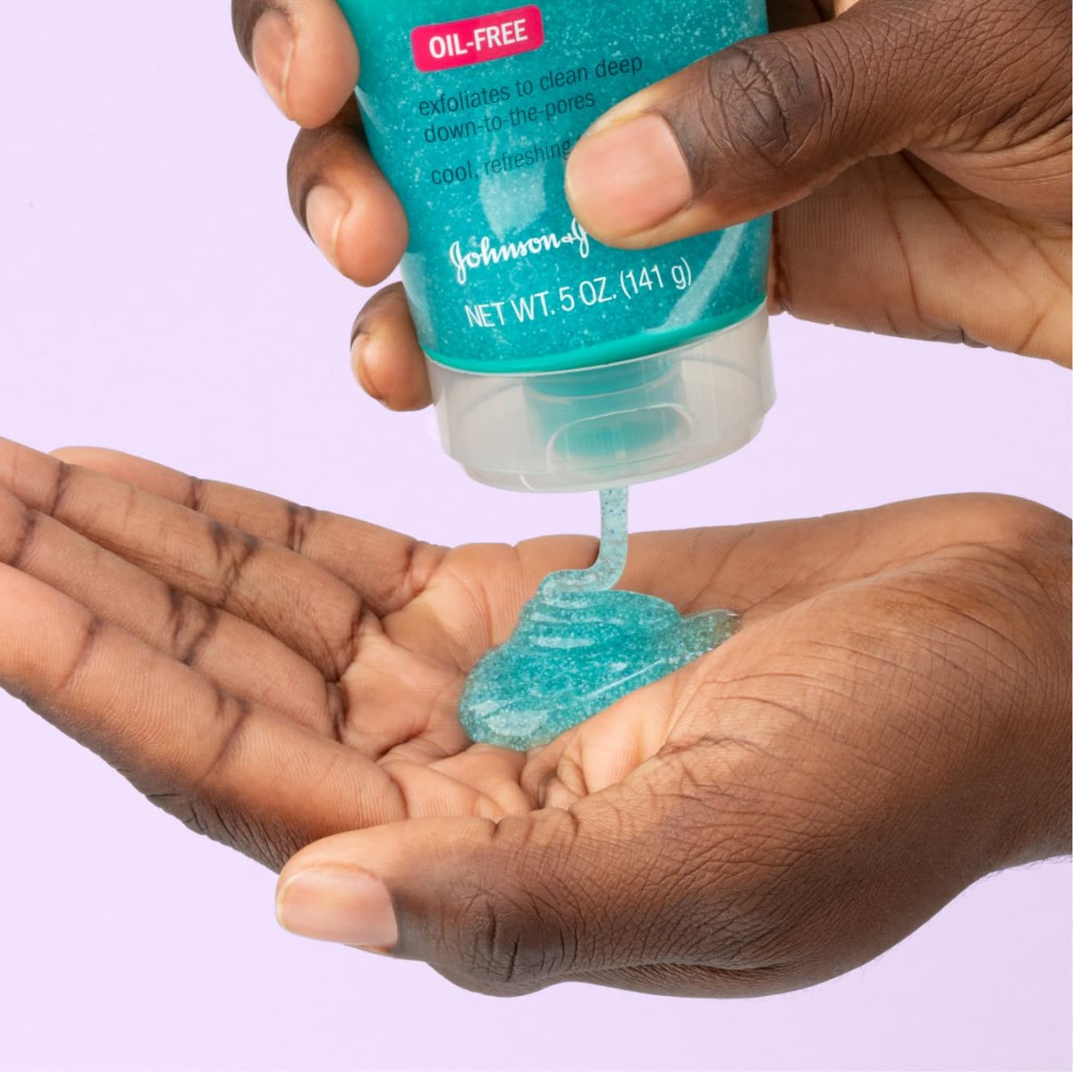 Turquoise Clean & Clear deep action exfoliating scrub squeezed into palm in front of light purple background