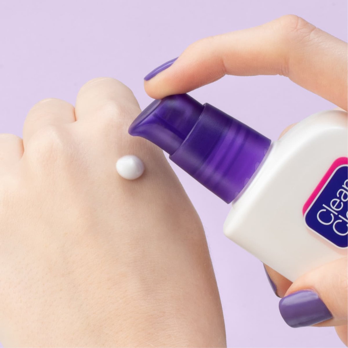 Hand with purple nails pumps Clean & Clear dual action moisturizer on back of fist