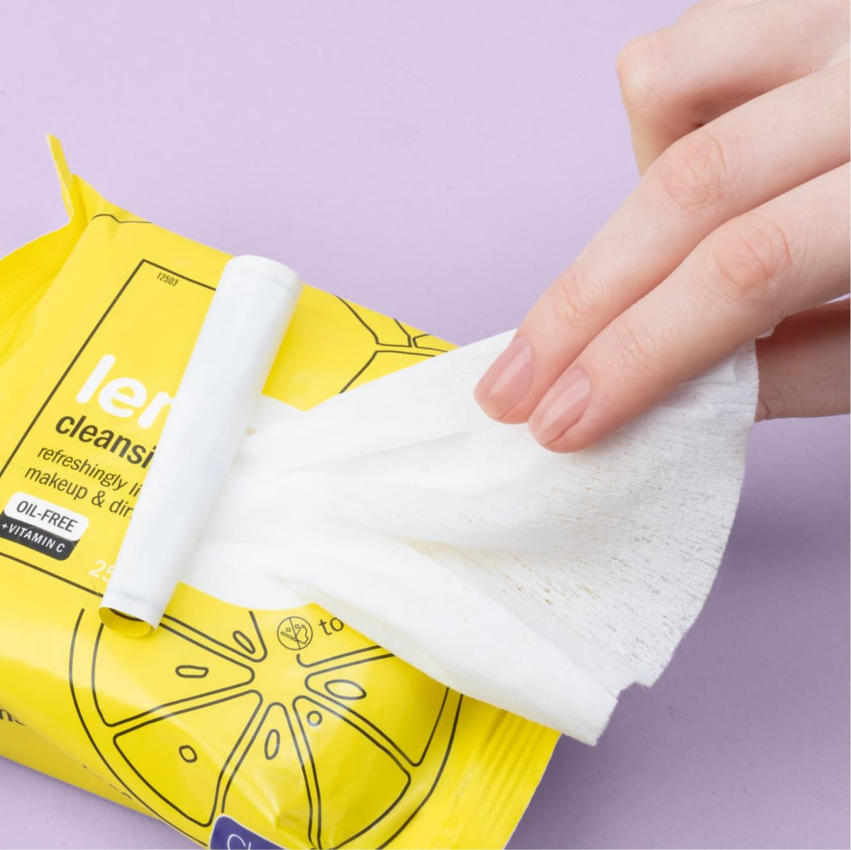 White wipe being pulled out of lemon cleansing wipes in a yellow packaging in front of a light purple background