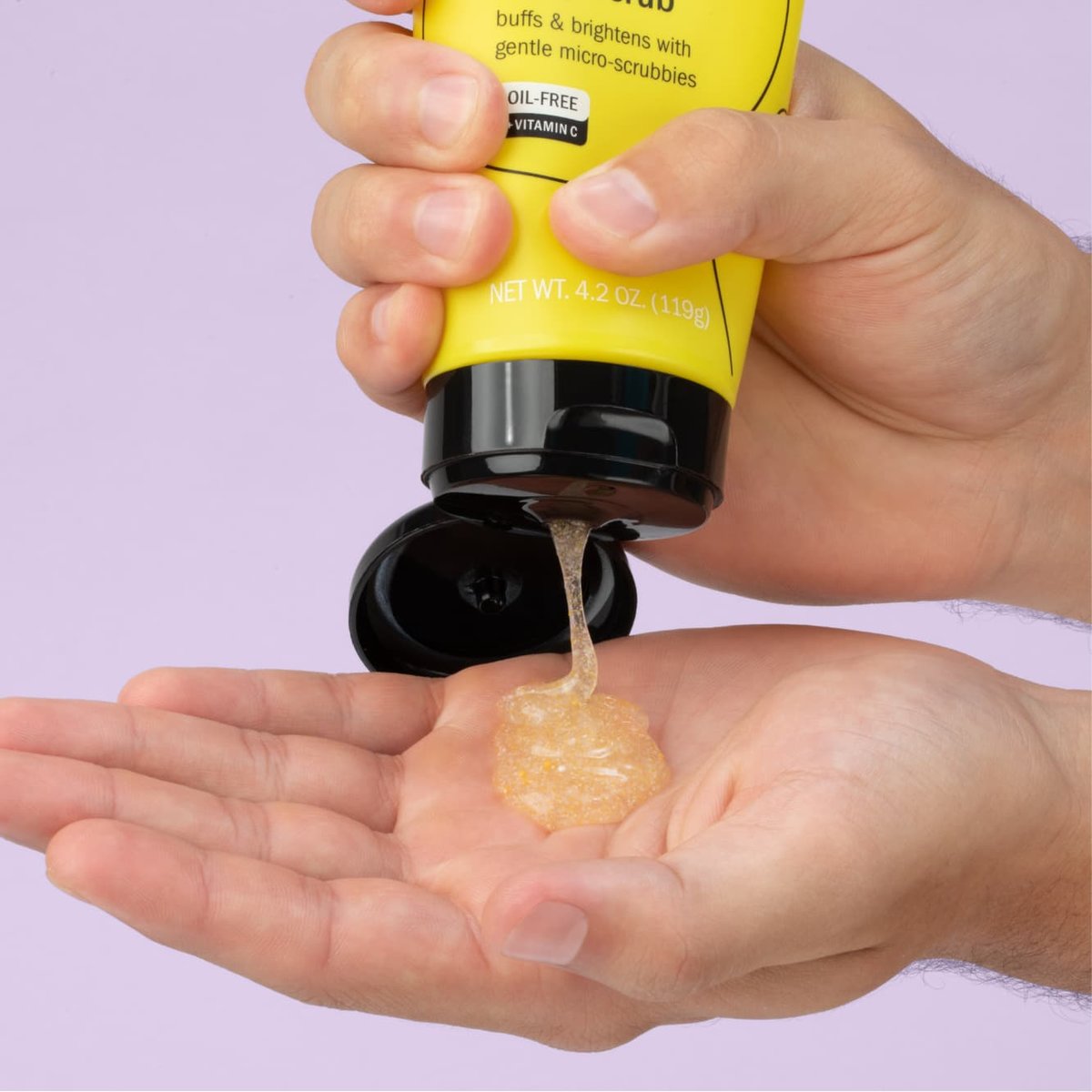 Clean & Clear lemon zesty scrub with yellow tube and black cap squeezed into palm of hand in front of light purple background
