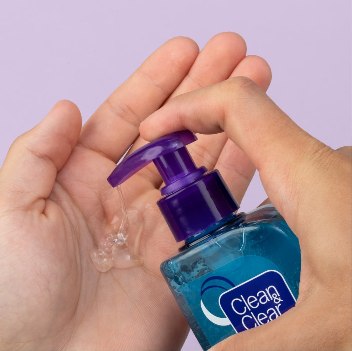Clear Night Relaxing face wash in blue bottle with purple cap is pumped into palm of hand in front of light purple background