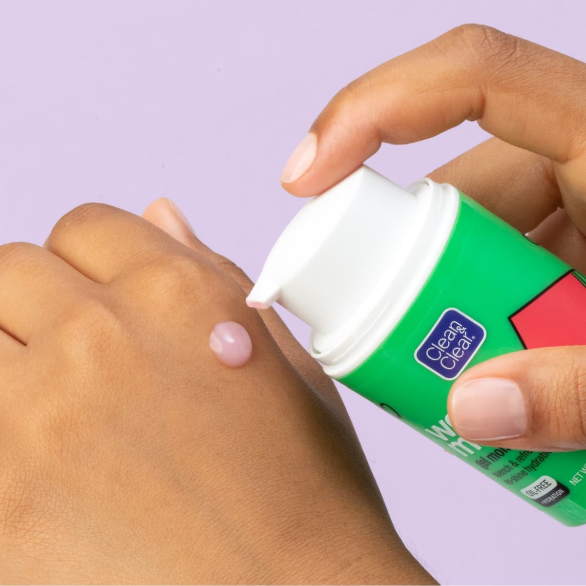 Drop of watermelon gel moisturizer is pumped from green bottle with white top onto back of fisted hand in front of light purple background