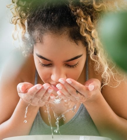 Woman splashing water on her face to start the day