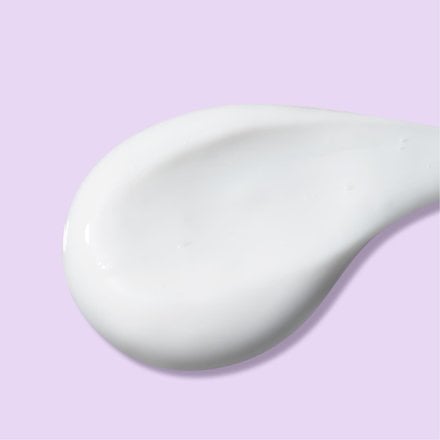 Dollop of dual action moisturizer in front of light purple background