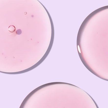 Close up of pink circles of watermelon gel cleanser in front of light purple background