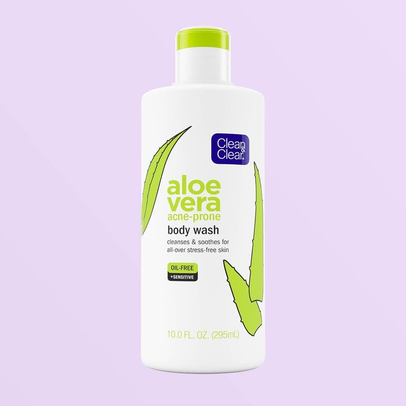 White squeeze body wash bottle with green text and aloe leaves over purple background