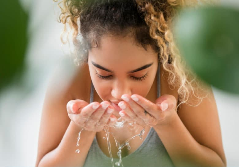 Woman splashing water on her face to start the day